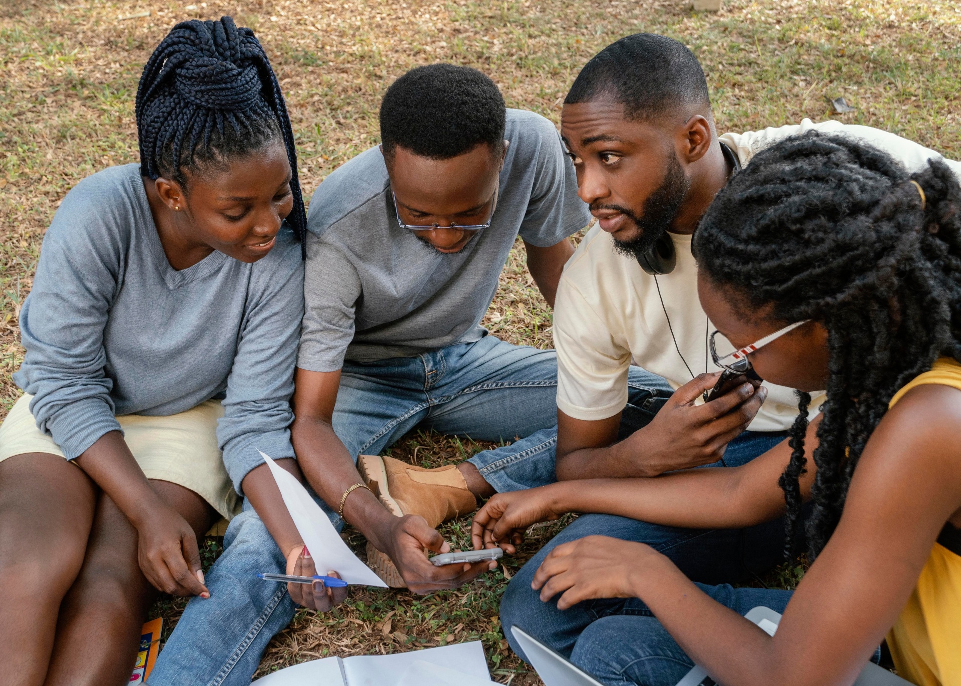 A group of people sitting together outdoors, discussing notes and sharing information.