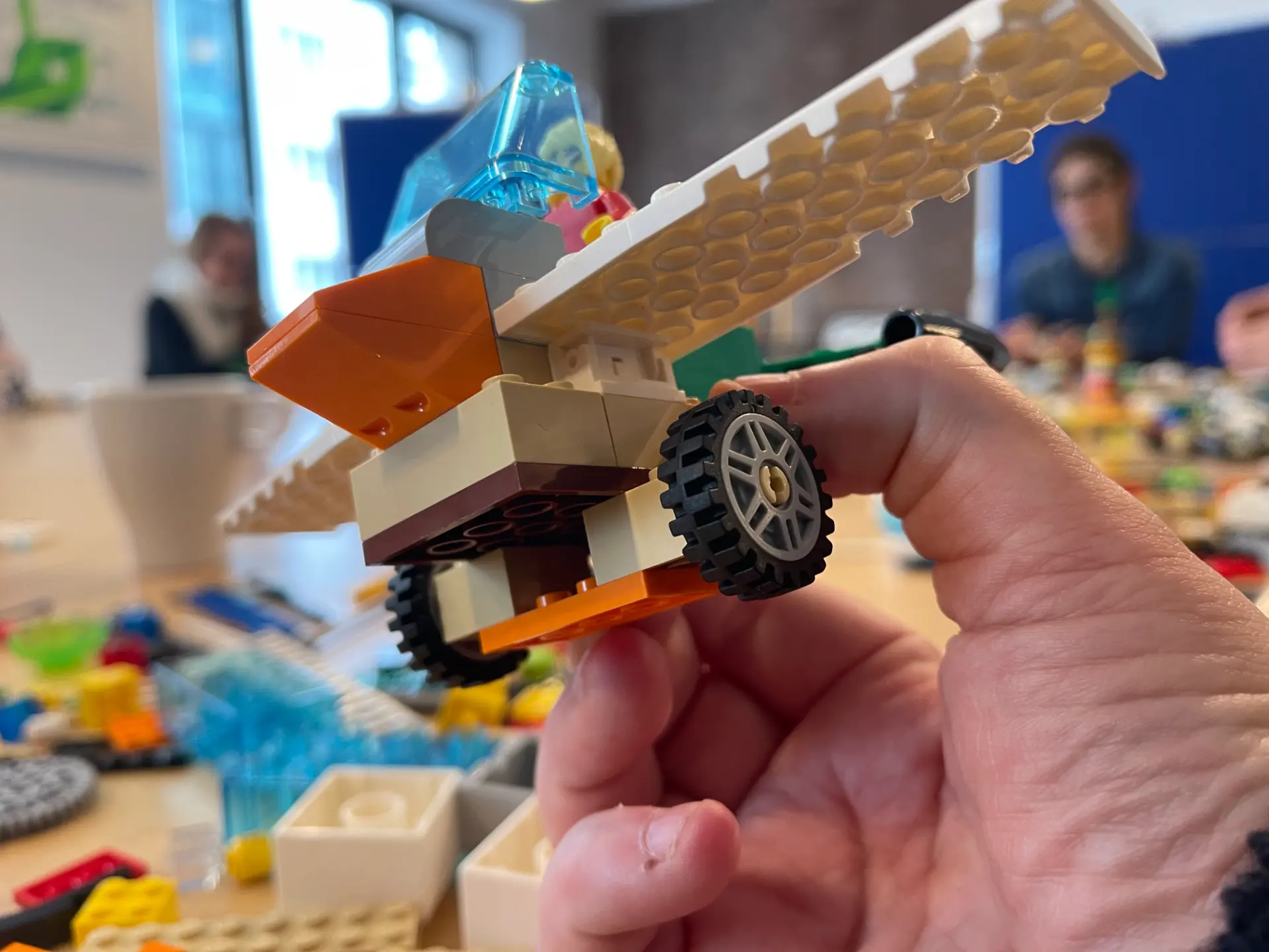A hand holding a detailed LEGO model built during a workshop